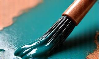 A ceramicist applying a vibrant glaze to a finished bowl